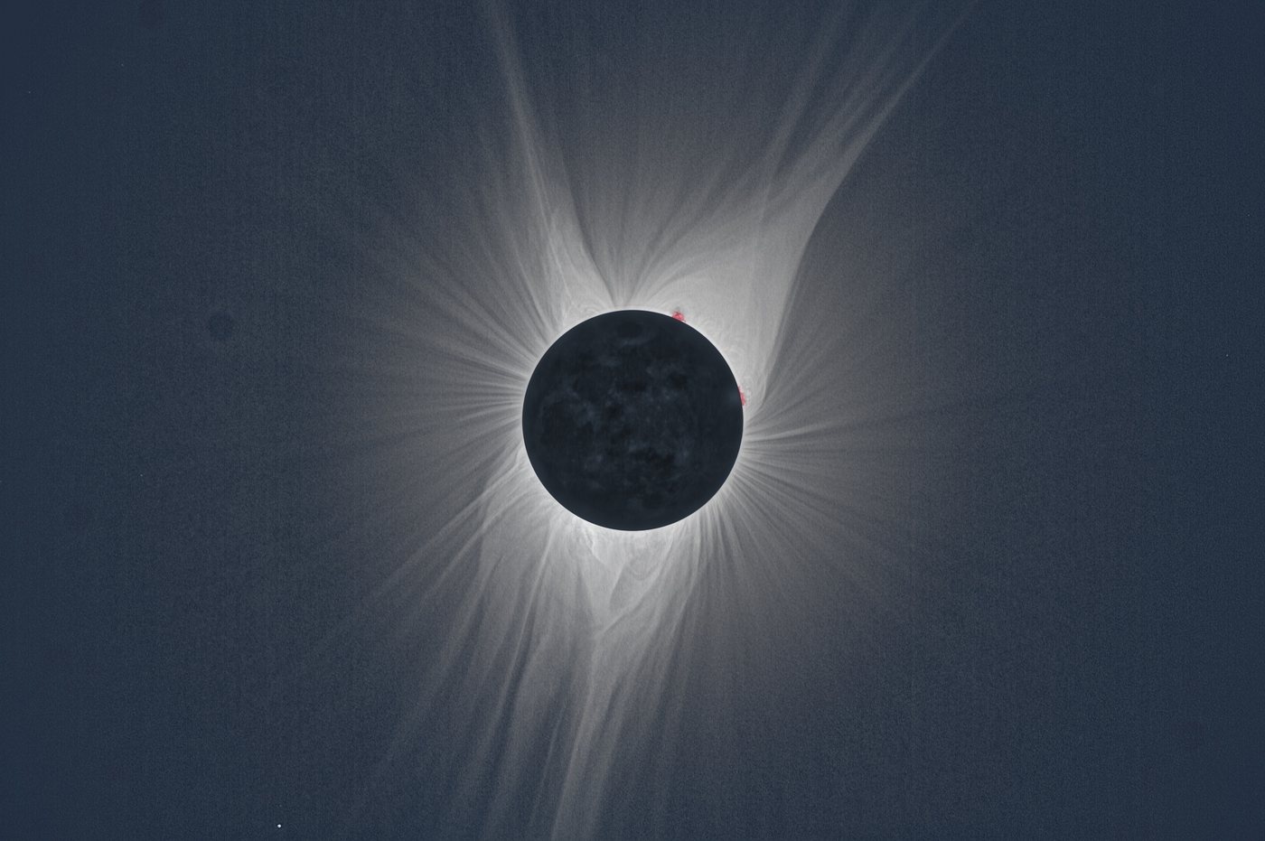 Total solar eclipse corona at solar minimum, 2017: polar plumes above and below, long equatorial streamers to either side.